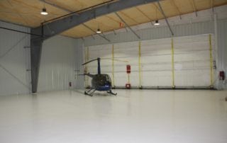 helicopter inside steel building with wide opening door