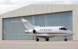 jet aircraft outside metal hanger with wide opening doors