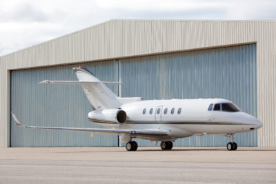 jet aircraft outside metal hanger with wide opening doors