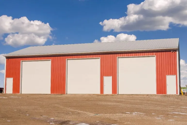 Red steel farm building with large overhead doors