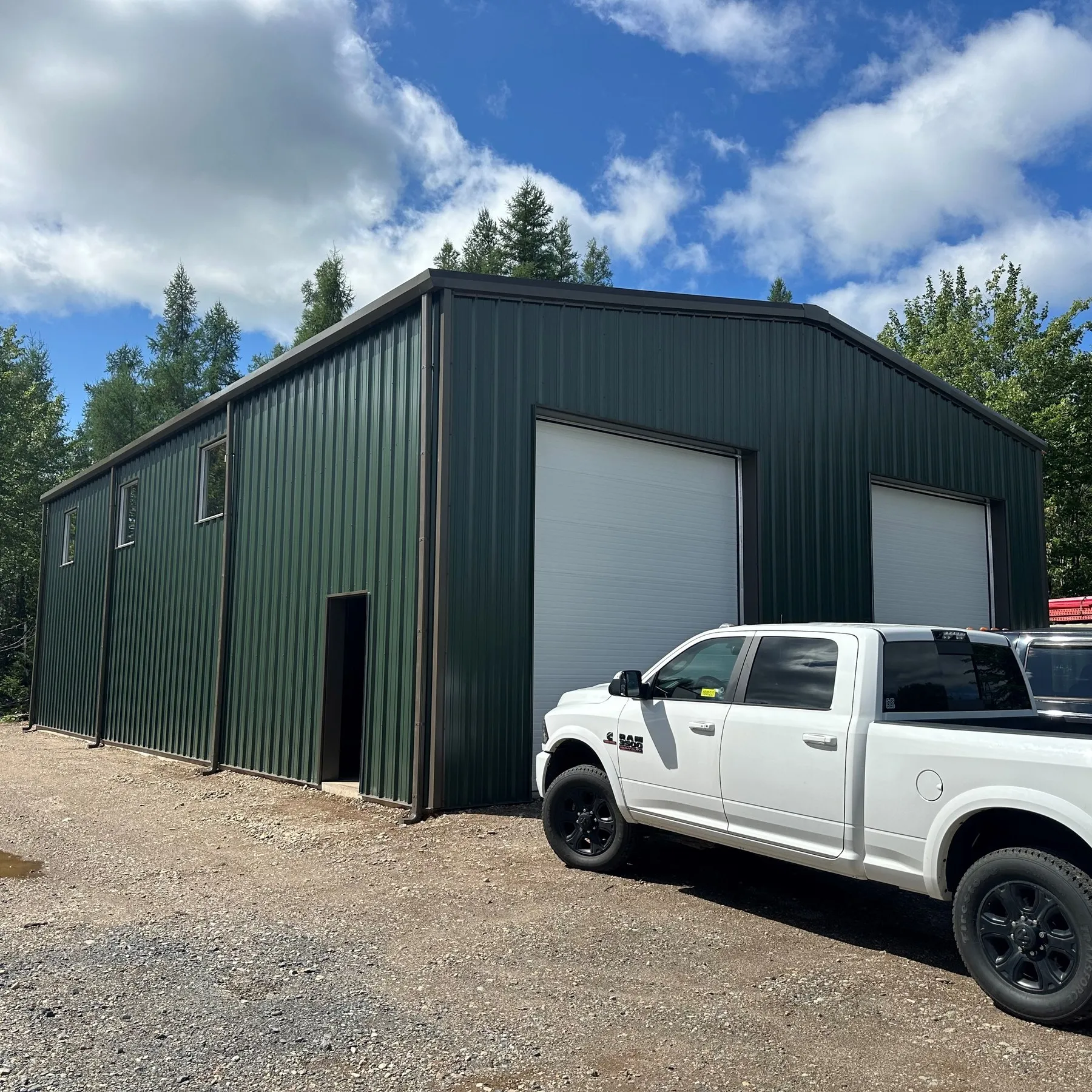 Green steel shop building with a pickup truck parked outside