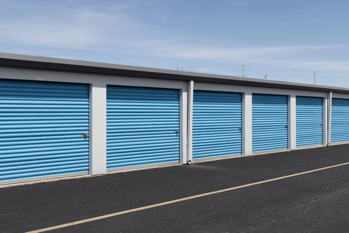 Row of blue roll-up doors on a steel self-storage building
