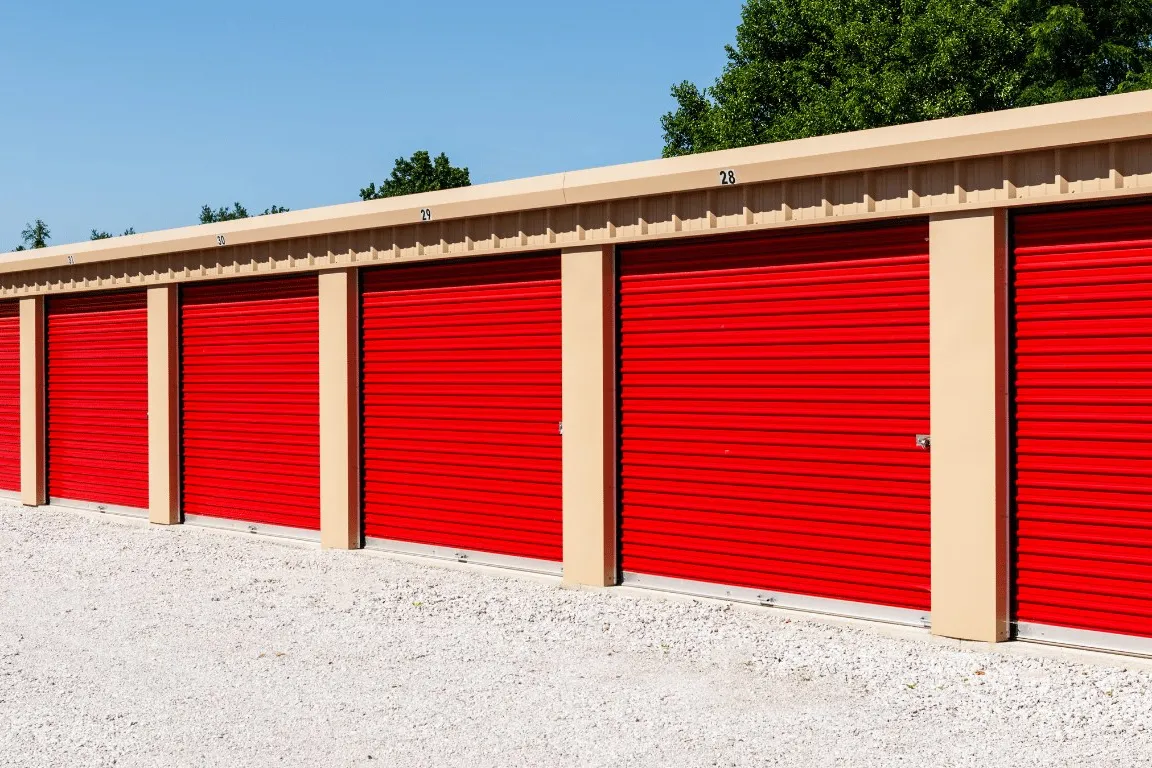 Row of red roll-up doors on a steel self-storage building