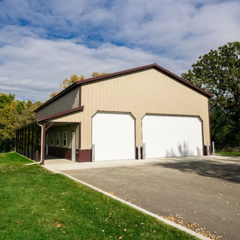 Tan steel building with two overhead doors and a covered porch