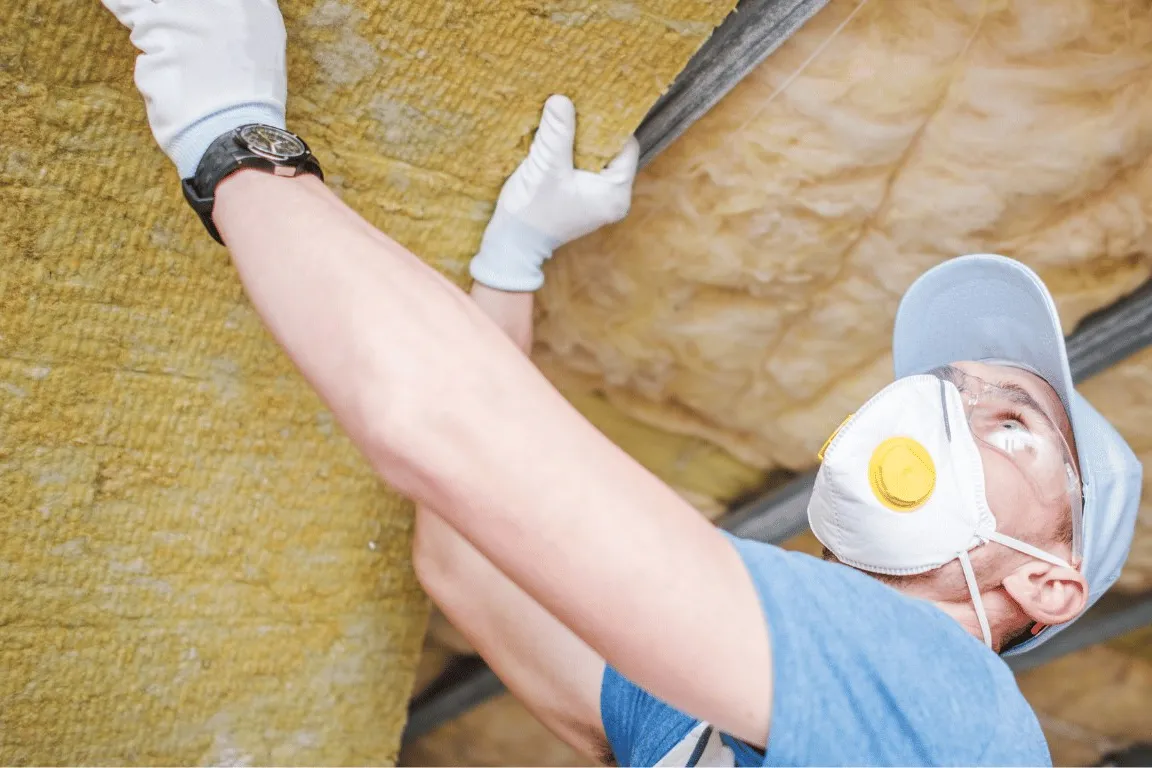 Installer fitting insulation into a steel building wall