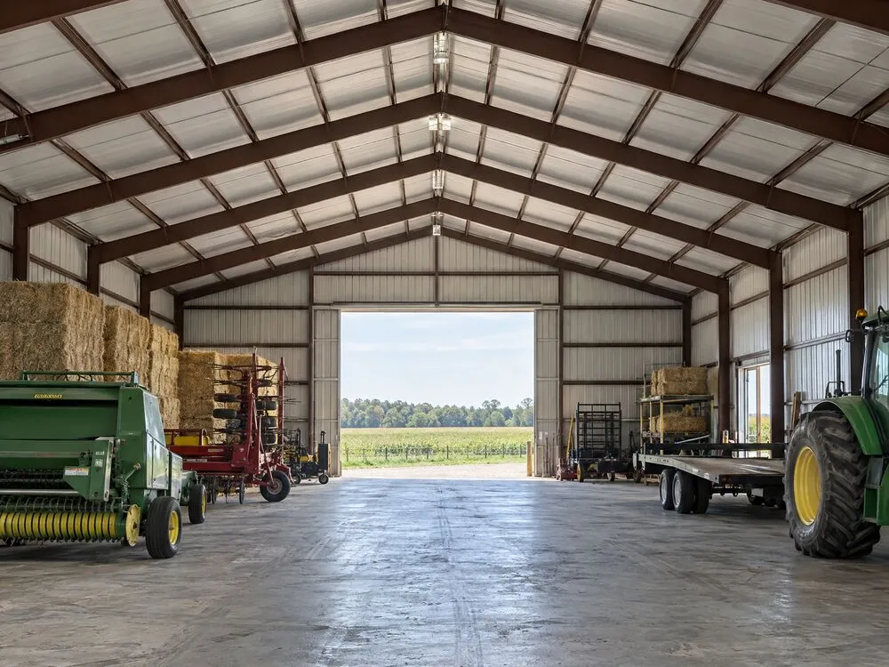 Clear-span steel farm building interior with hay, tractor and farm equipment