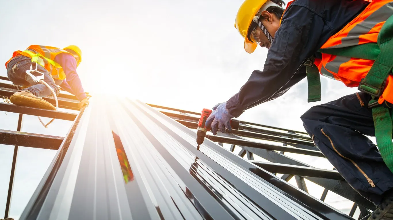 Installer fastening steel roof panels